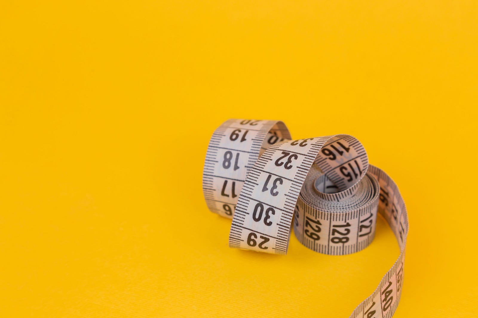 A tape measure, curled up against a yellow background. Being overweight or obese increases cancer risk. The American Cancer Society offers that excess body weight is responsible for about one out of nine (11 percent) cancer in women and one in 20 (five percent) in men. Too much weight is linked with approximately seven percent of all cancer-related deaths.