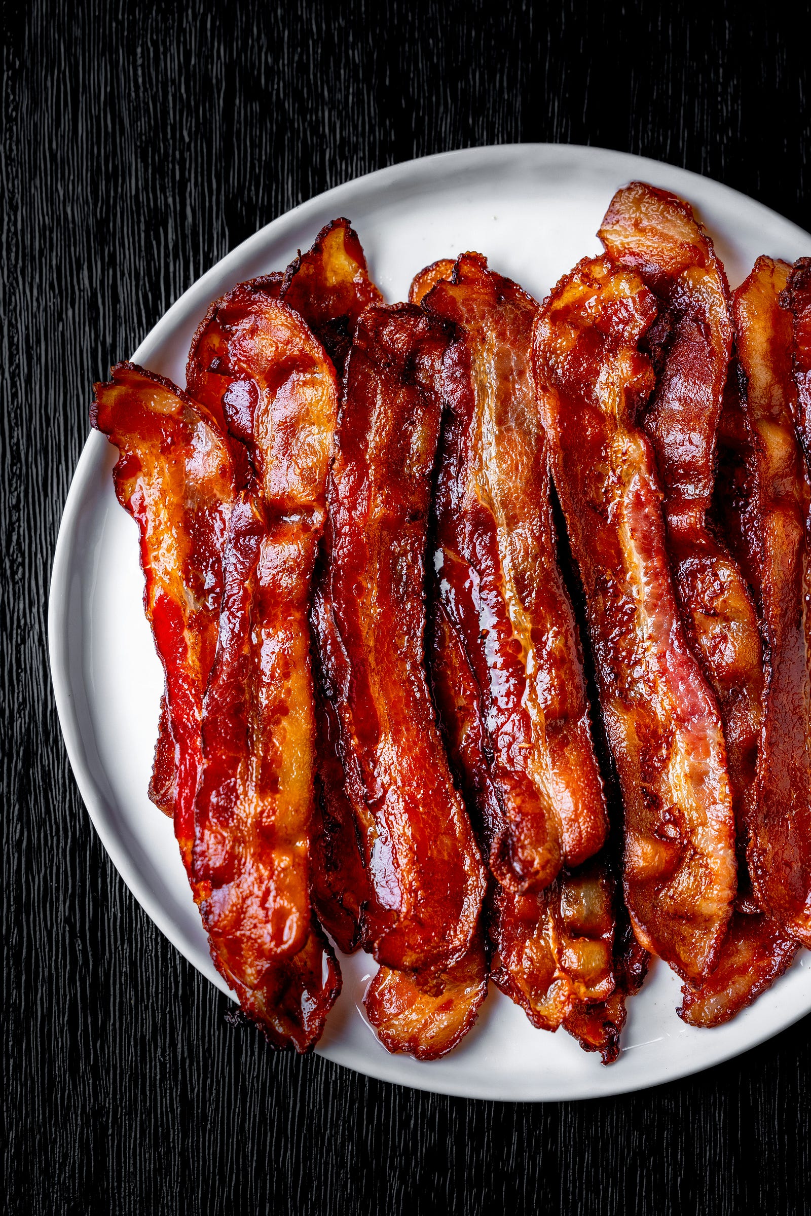 Slices of cooked bacon fill a plate.