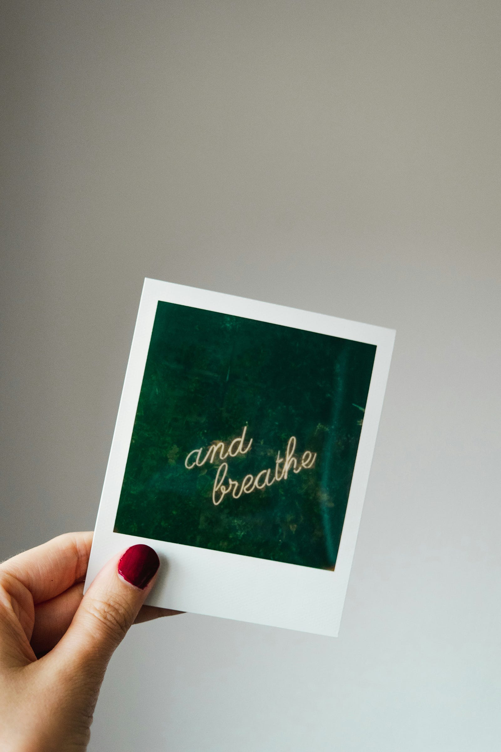 A Polaroid photo with the words “and breathe” in cursive.