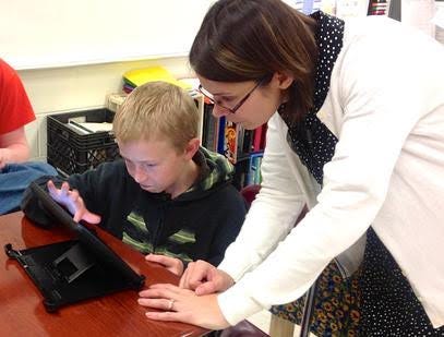 Debra Rook works with a student on a tablet. 