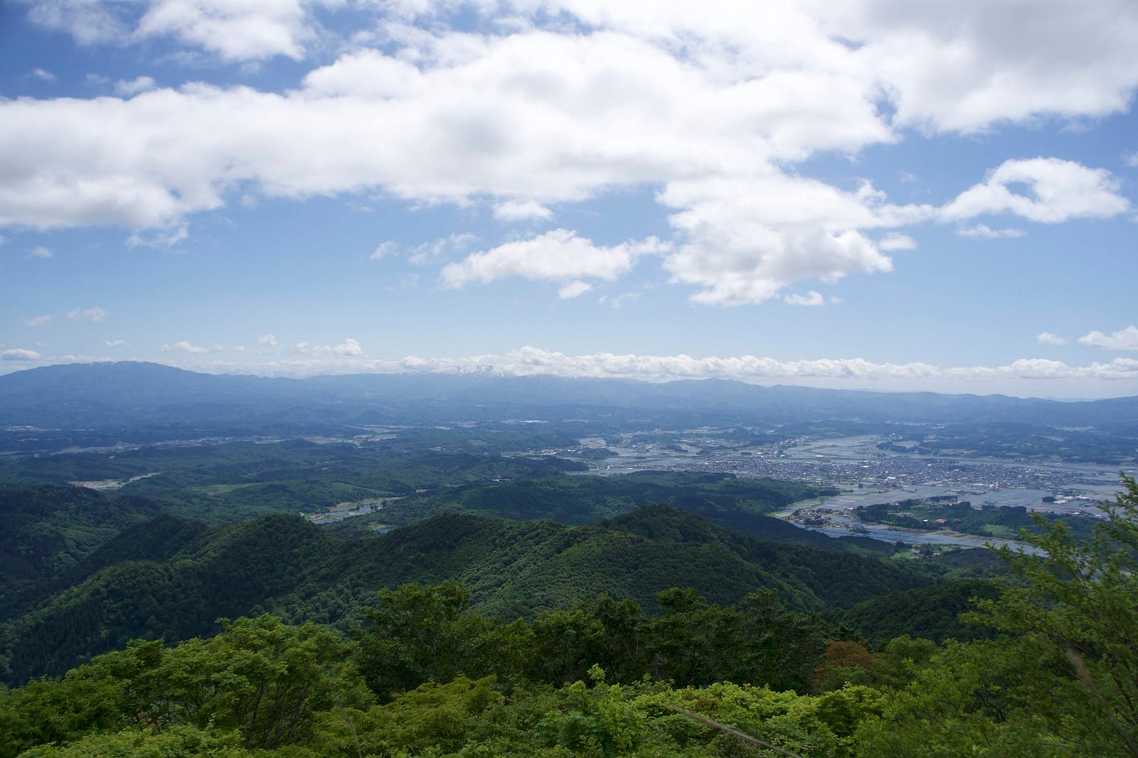 A view of Murayama Ha-yama, Mt. Gassan covered in cloud, and Shinjo City and the Shinjo basin in northern Yamagata Prefecture.