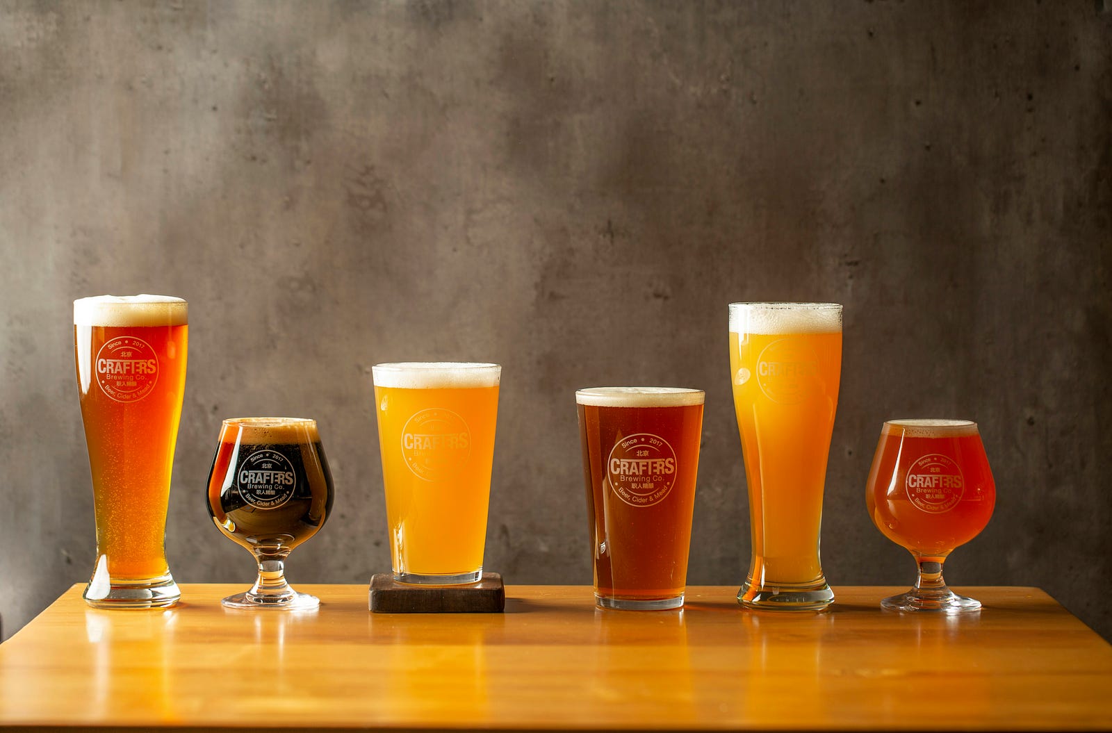 Six glasses of ale of various colors. The glassess vary in shape and height.