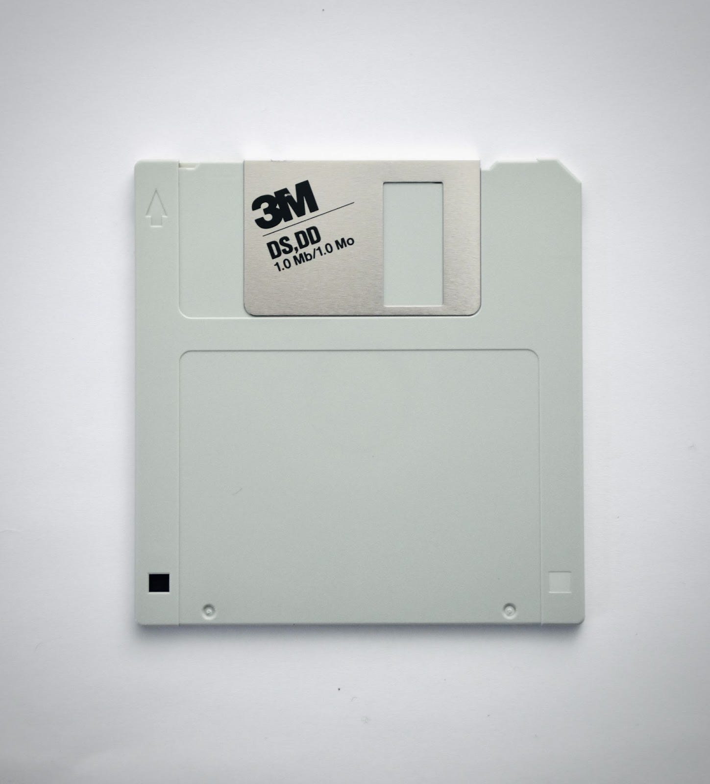 Photo of an old, grey 3.5 inch floppy disk with a 3M logo on it.