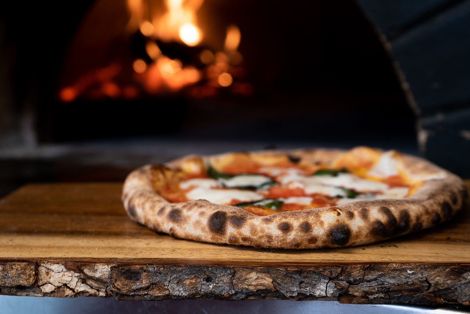 A pizza sits in front of a wood-fired oven. Too much (or too little) salt is bad for health.