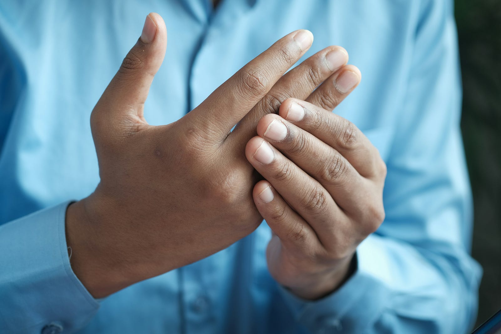 A person with arthritis holds one hand with the other.