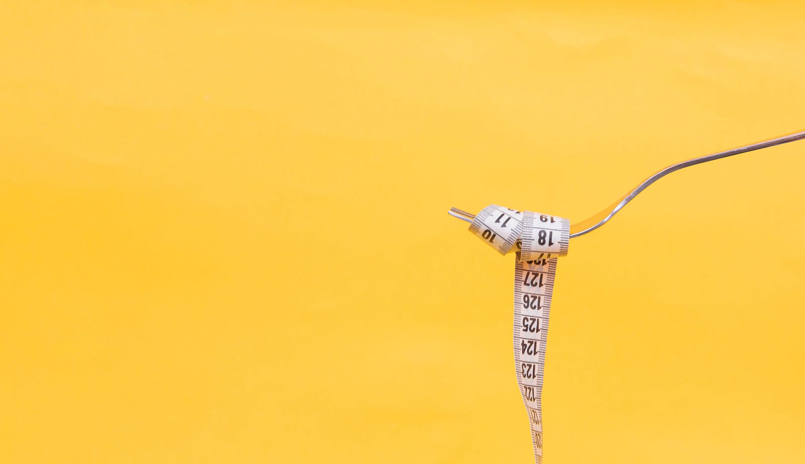 A fork extends from the right to hold a tape measure. Mustard yellow-colored  background. Running can facilitate weight loss.