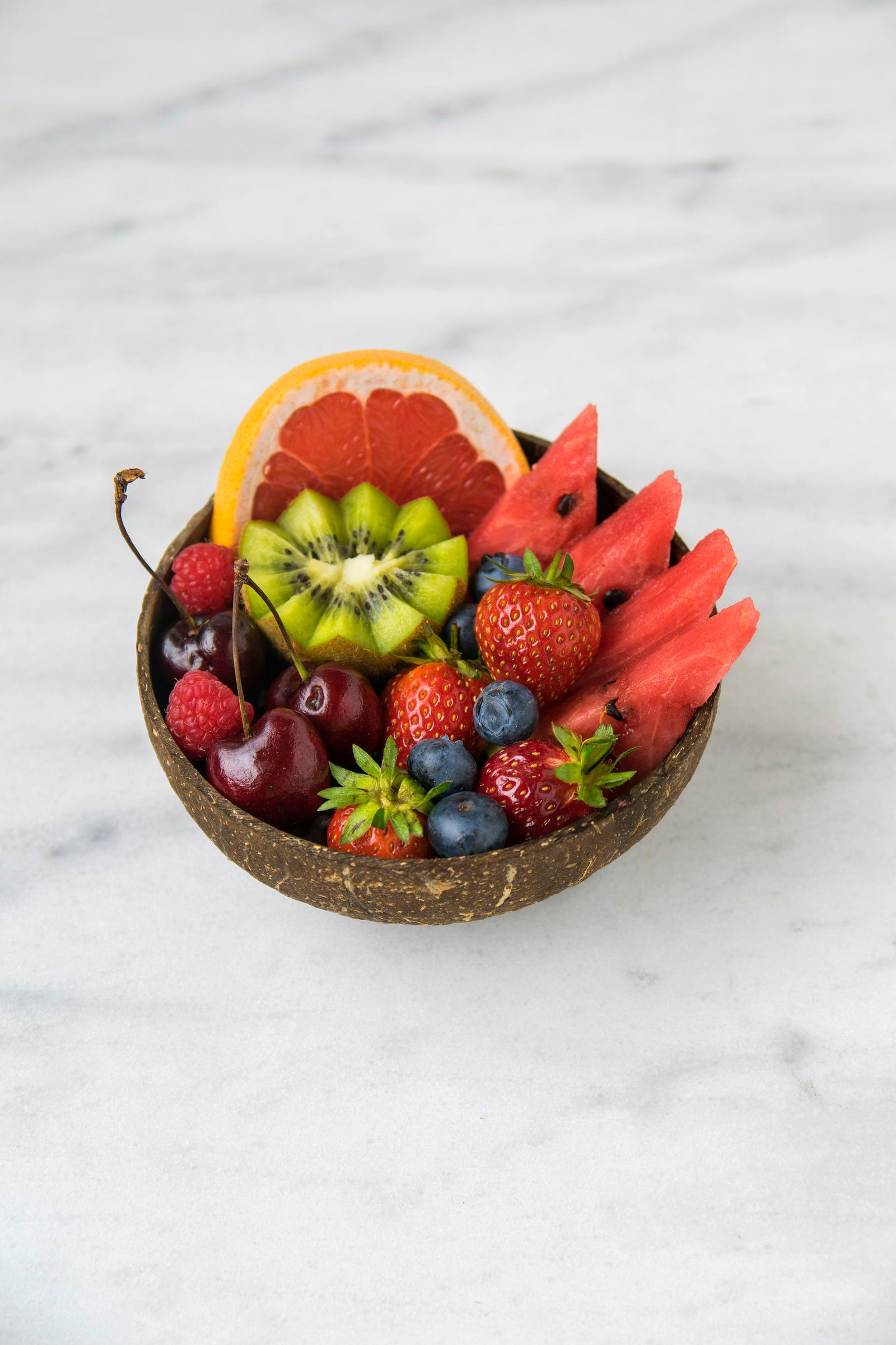 A bowl of fruit, including blueberries, strawberries, watermelon, kiwi, and honeydew melon.