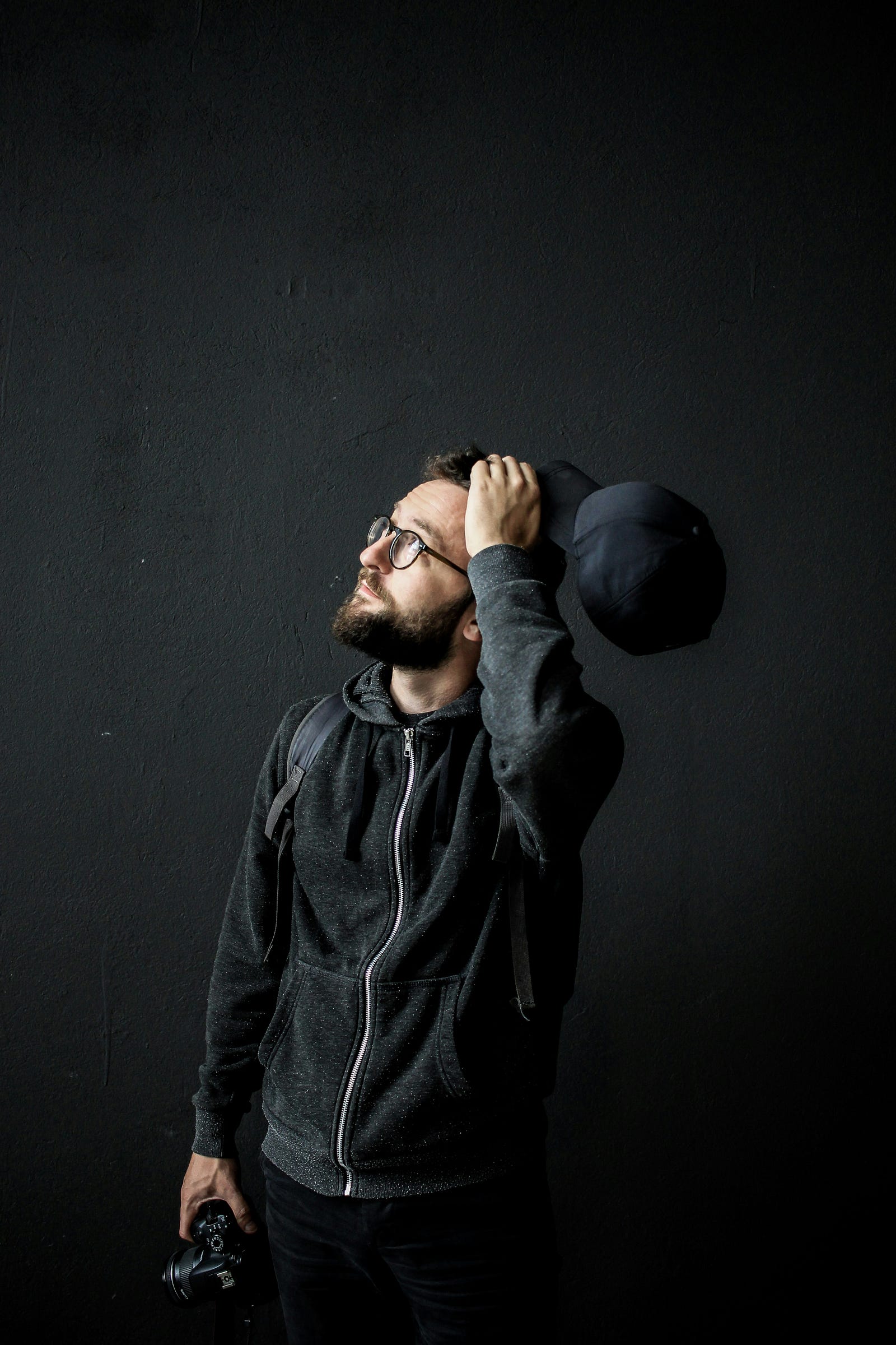 A man touches his head as he looks up in a questioning way.