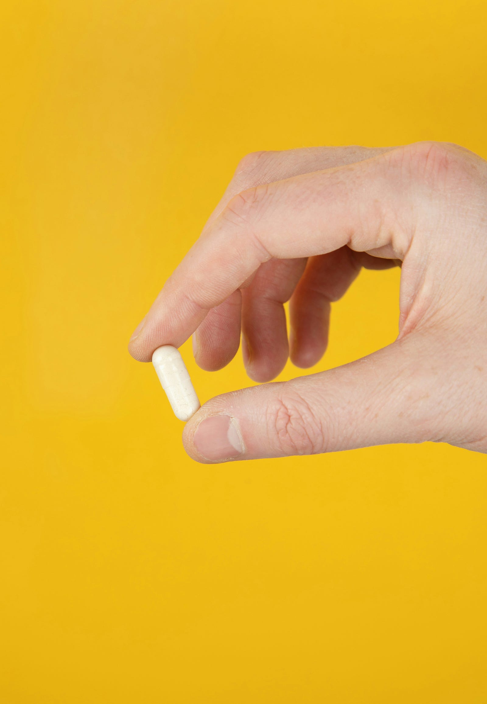 A hand extends from the right to hold a vitamin D pill.