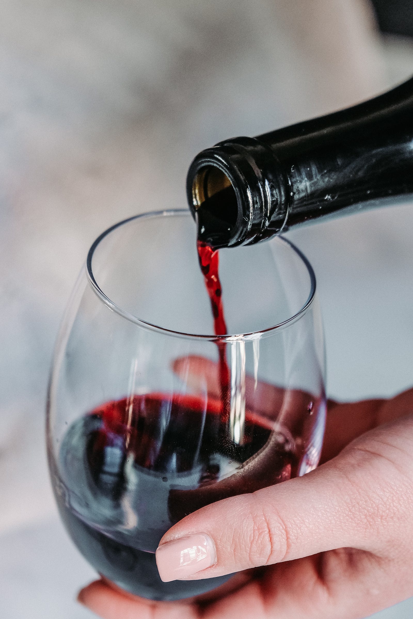 A bottle extends, from the upper right of the image, to pour red wine into a glass. Antioxidants (polyphenols) in red wine may help protect the lining of blood vessels in the heart. The polyphenol resveratrol is one part of red wine that’s been noted to be health-promoting.