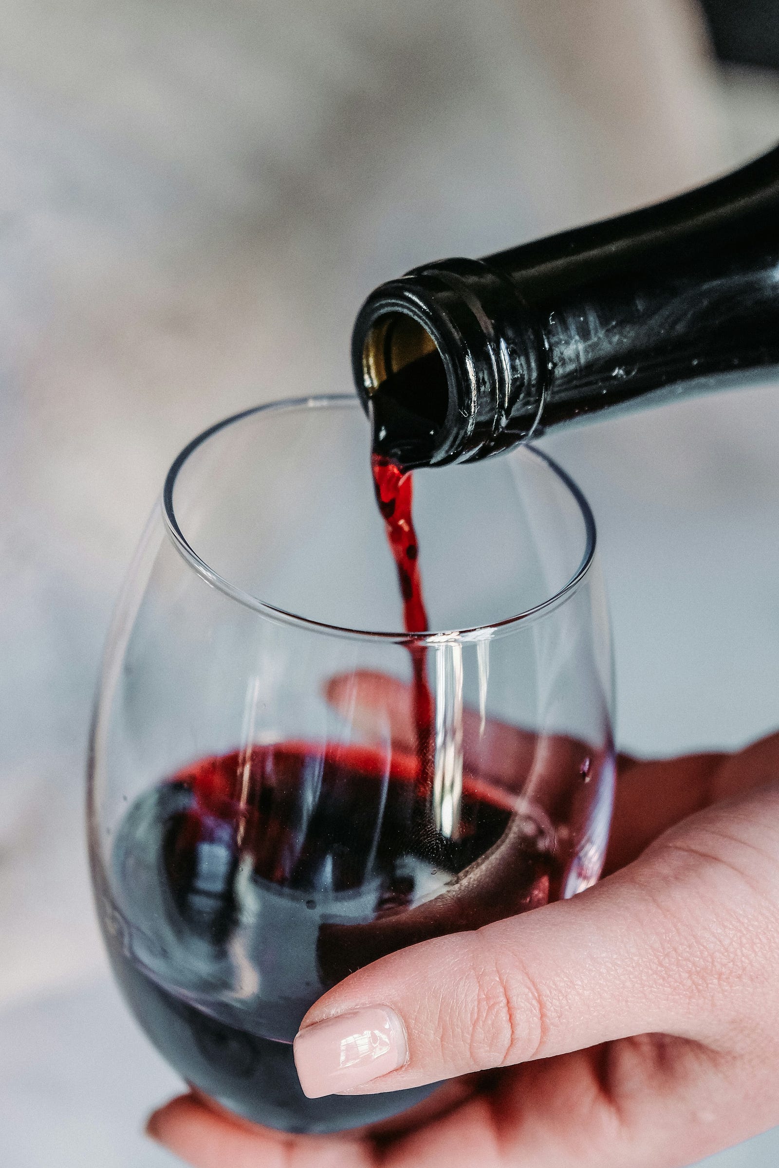 A person pours red wine into a glass they hold with their opposite hand. If you regularly drink alcohol, it can be harder for your body to absorb folate.