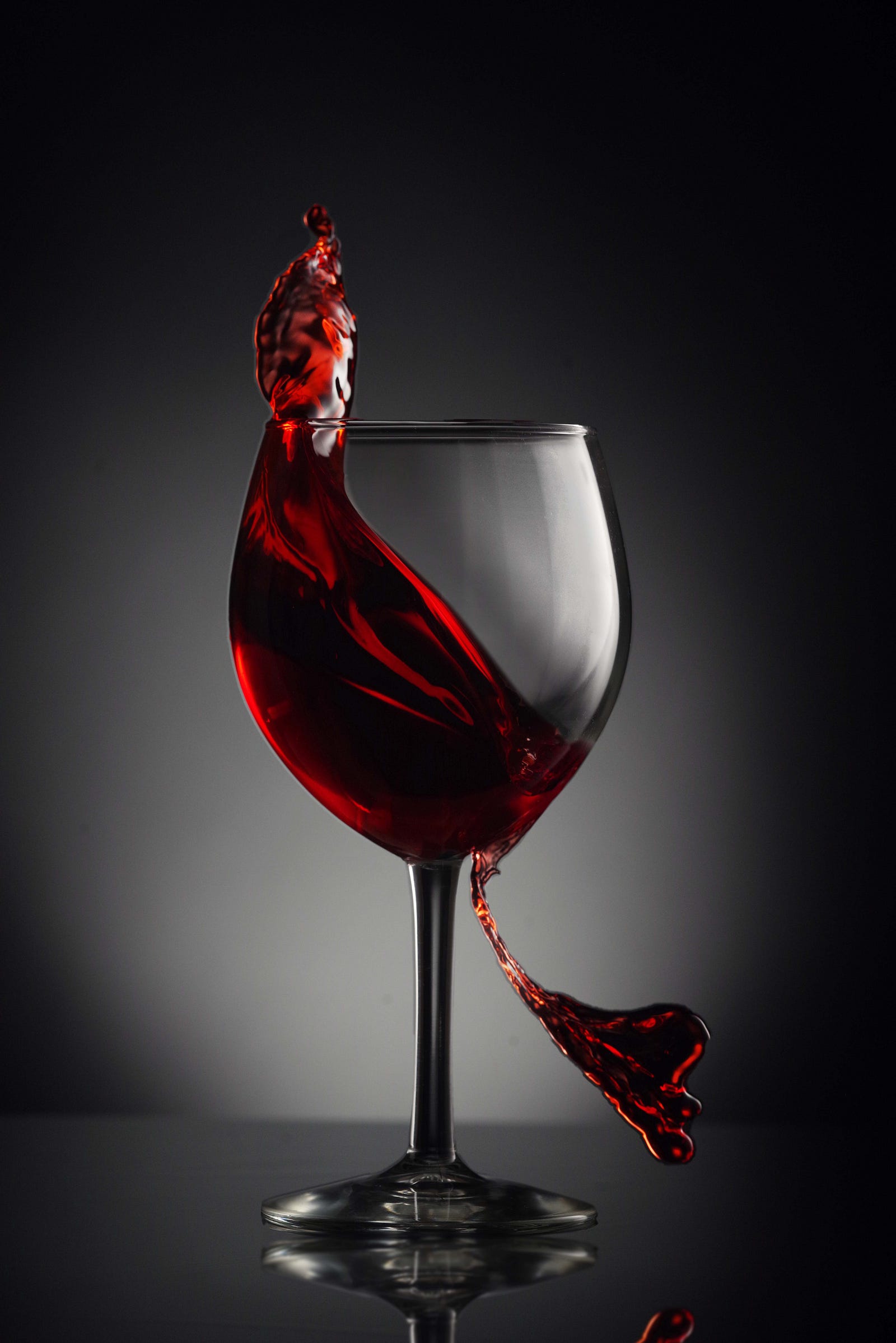 Red wine splashes out of a glass as it is poured in from above. Moderation might be a key to reaping the alleged health benefits of red wine.