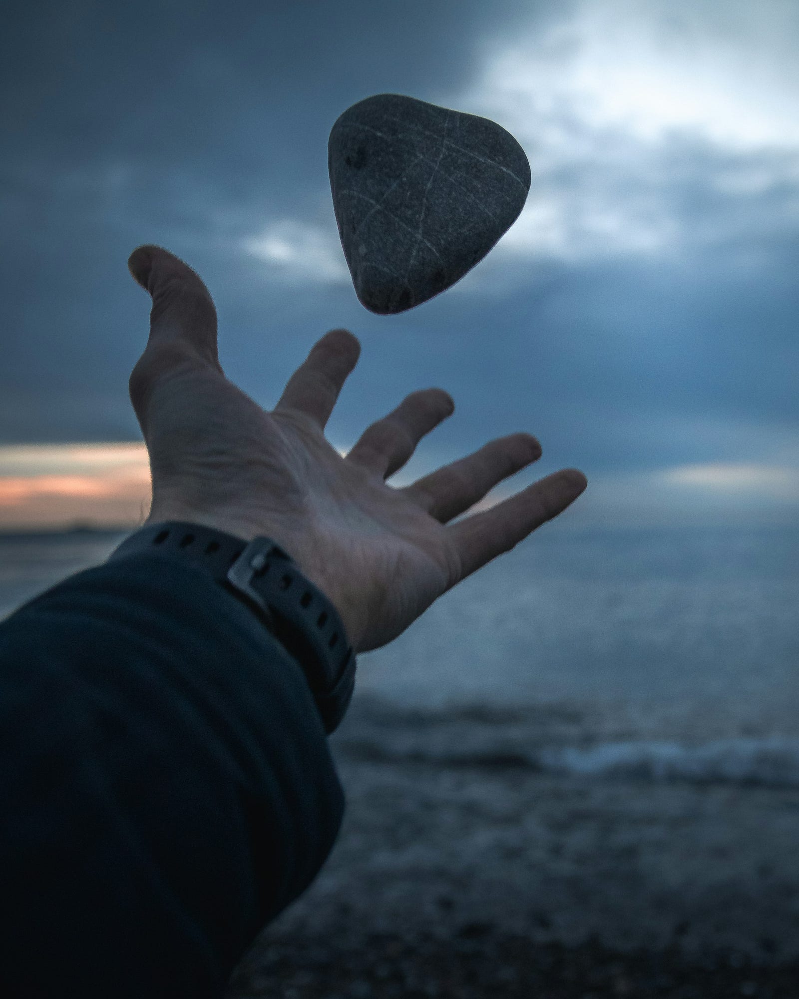 A hand tosses a rock into the air.
