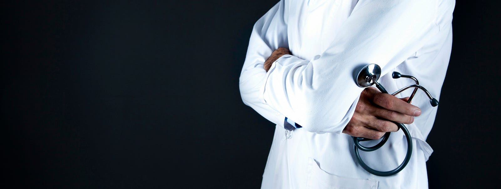 A doctor in a white coat folds their arms, stethoscope in hand. Managing chronic diseases can help lengthen healthspan and longevity.