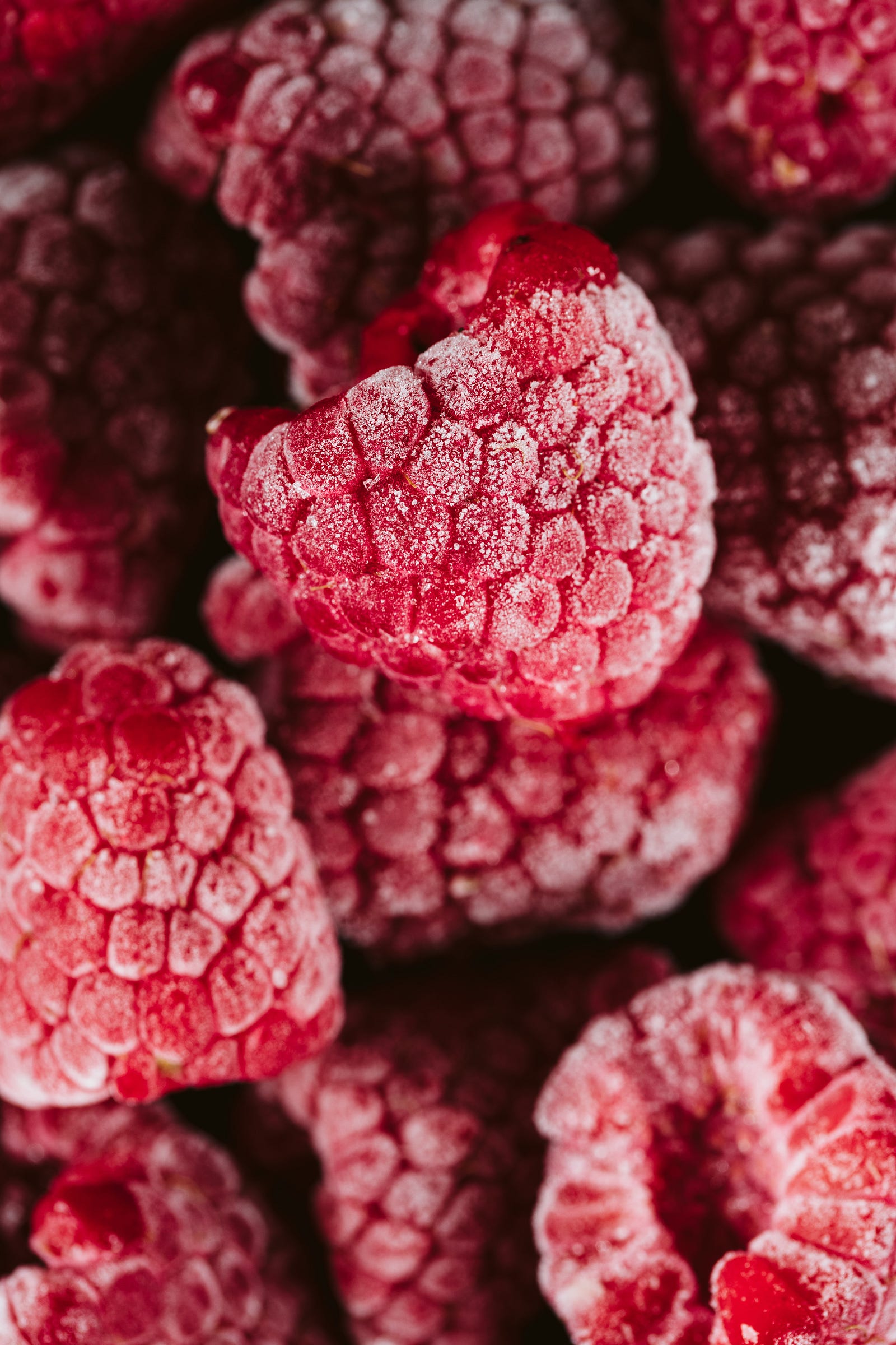 Frozen raspberries in extreme closeup. Did you know that frozen fruits sometimes have more nutrients than fresh? For example, this may be the case if the frozen variety had been picked at peak ripeness.
