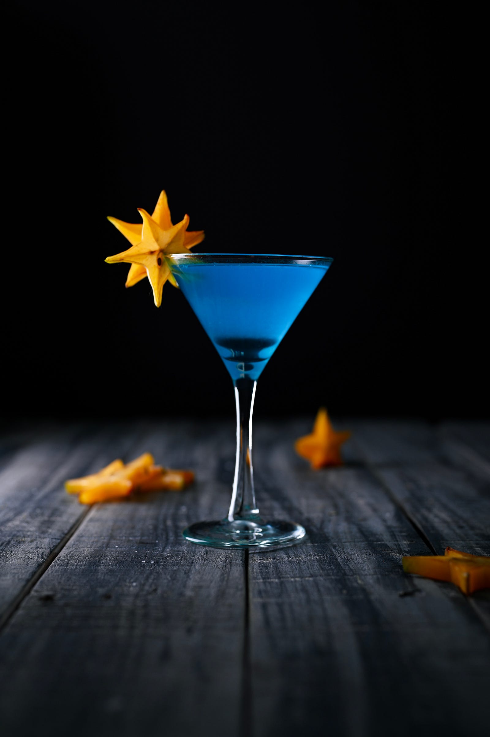 A blue beverage is seen in a V-shaped glass. Observational studies show a lower risk of cardiovascular disease with light to moderate alcohol intake than abstinence or heavy consumption. There appears to be a J- or U-shaped epidemiologic association.
