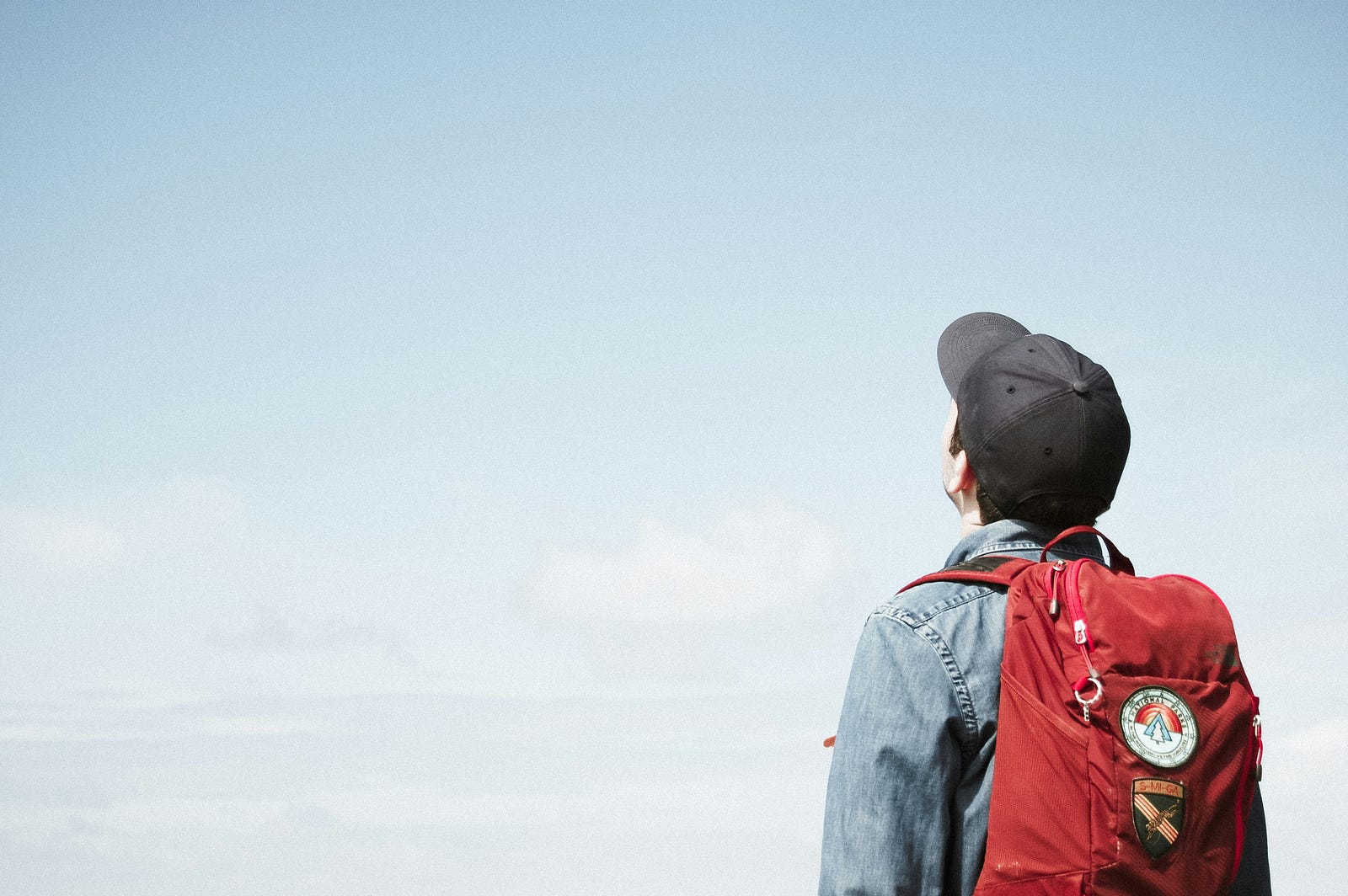 A young person looks up at the blue sky.