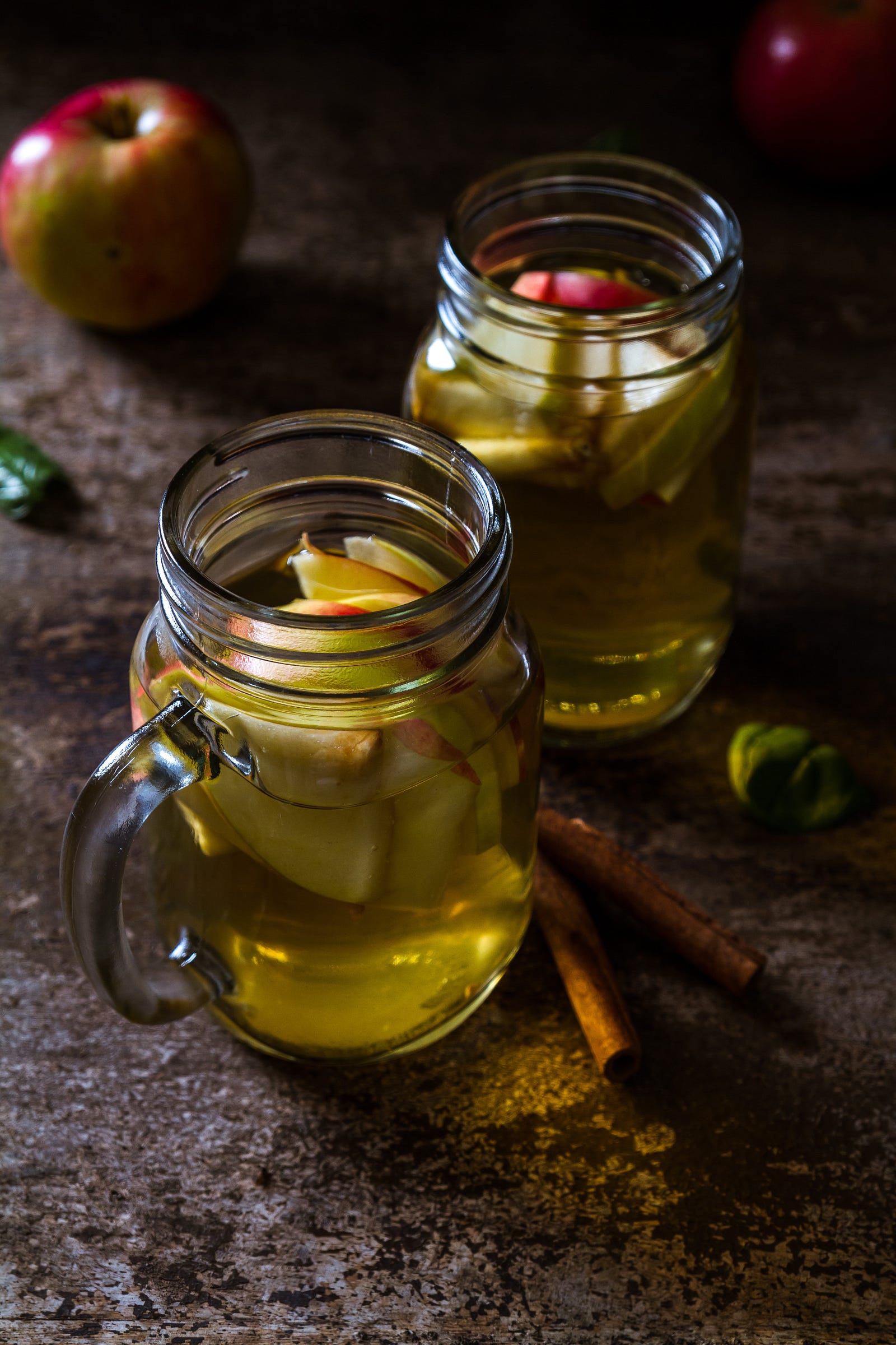 Two glass cups of vinegar, with sliced apple pieces within them. Legend has it that around 5000 BC, a Babylonian courtier “discovered” wine. The drink had formed from unattended grape juice. This finding eventually led to the discovery of vinegar and its utility for food preservation.