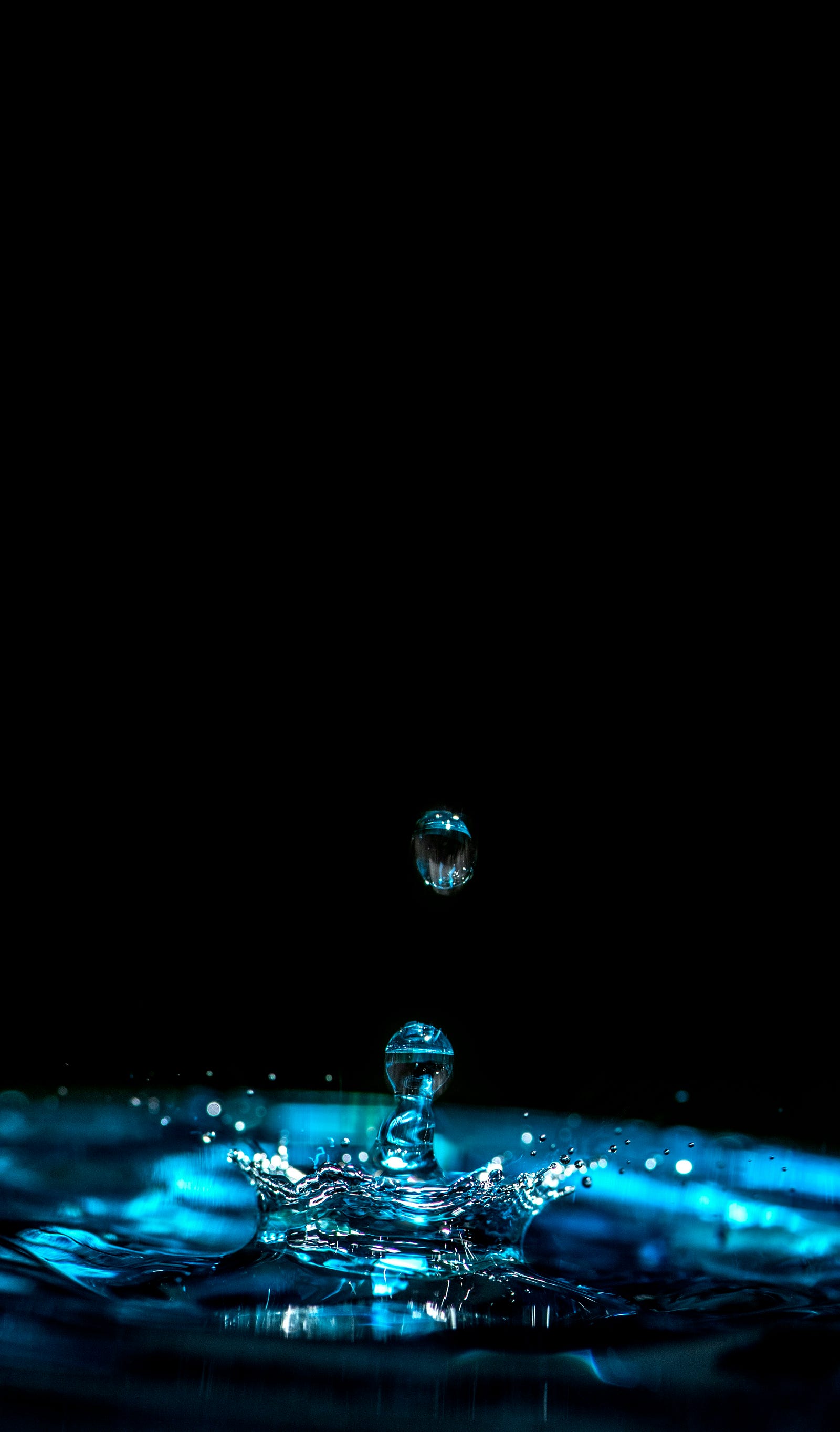 A water drop bounces up from a body of water.