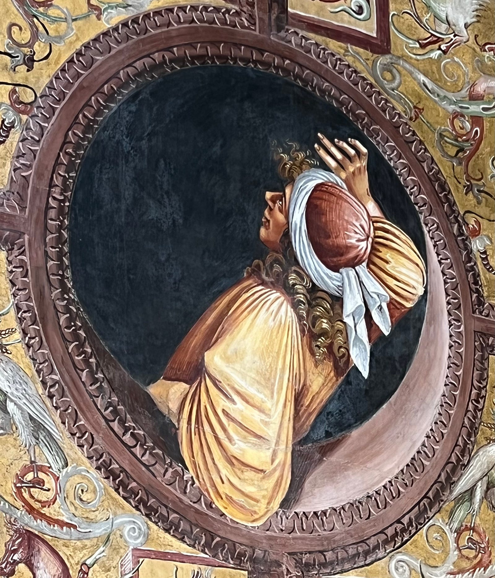 Photo of a painting in the Duomo di Orvieto of a mediaeval man looking out an open lunette at the scene above him.