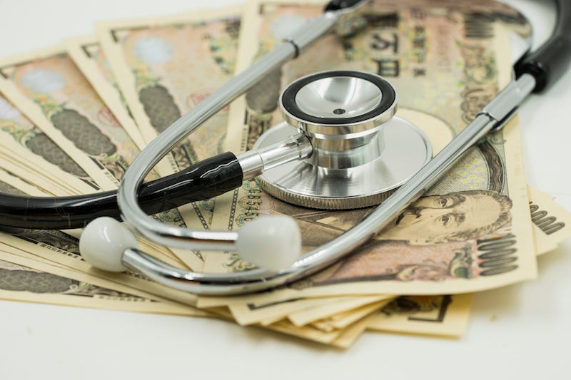 Someone pays for their hospital bill in Japan with a stack of 10,000 yen notes