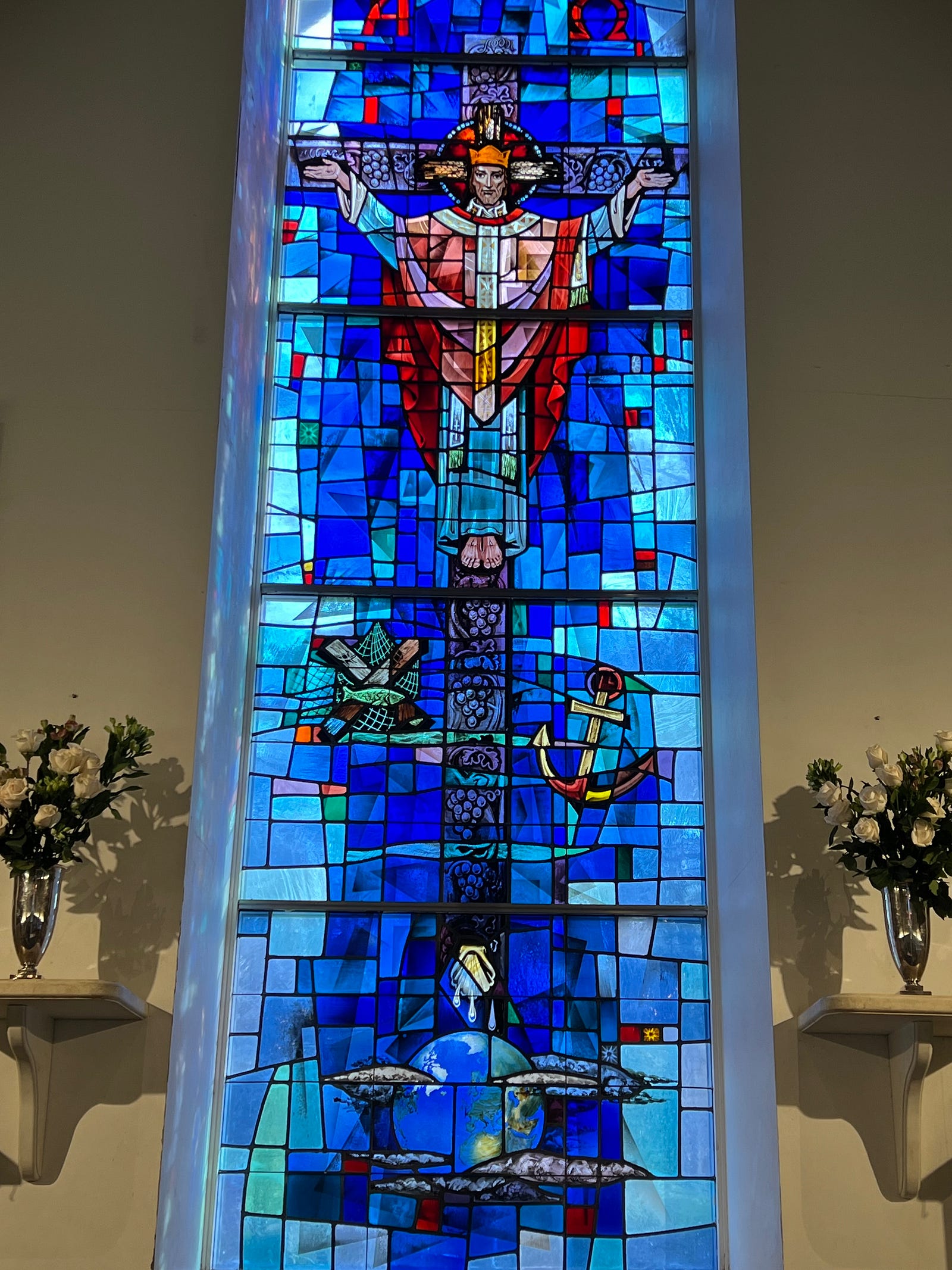 Photo of the altar window at St Andrew’s Madison, CT showing Jesus, up to his neck in the waters of chaos, and victorious on the cross.