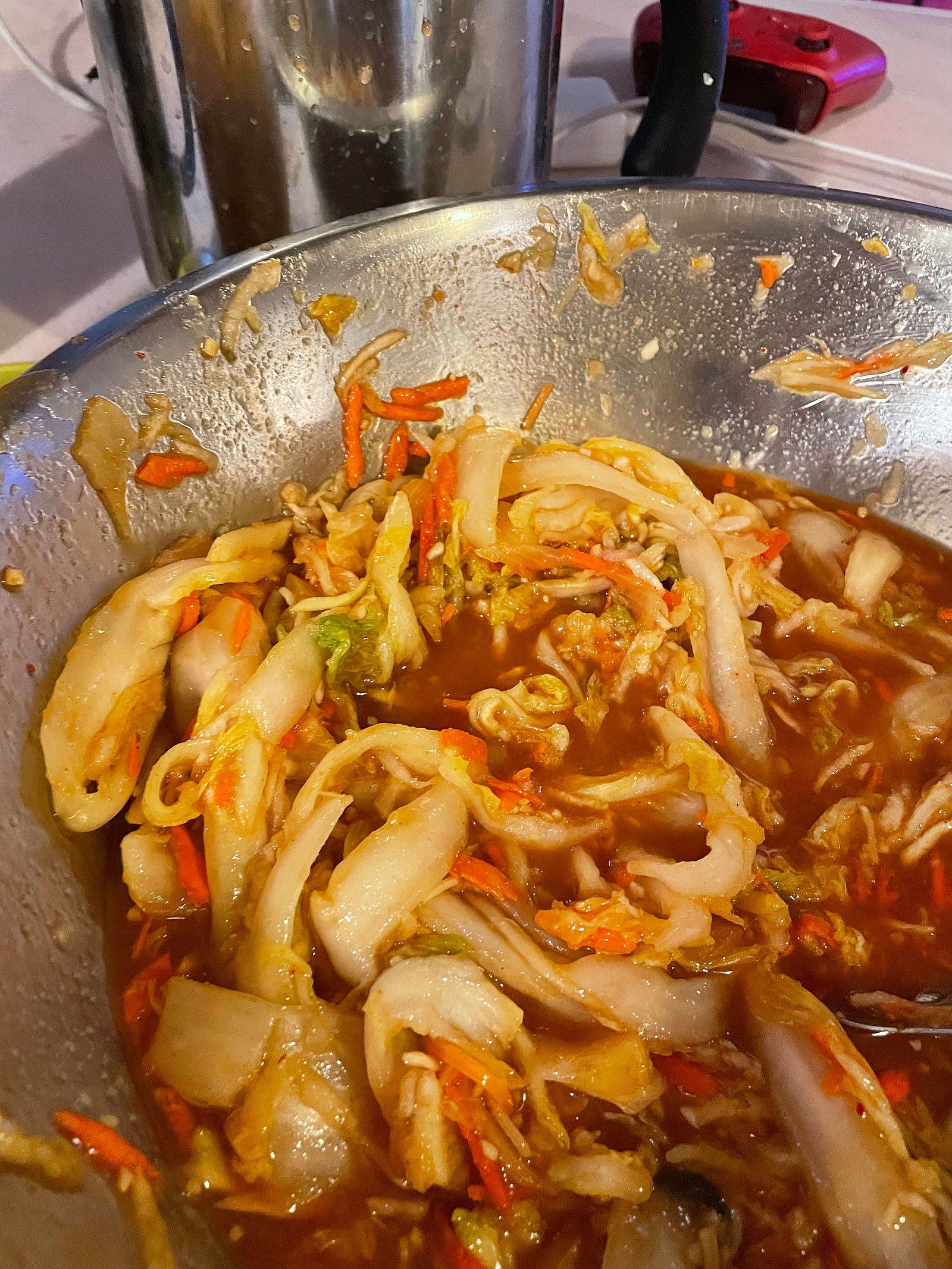 kimchi a pickled cabbage with root vegetables in a spicy red mainade filling half a large bowl.