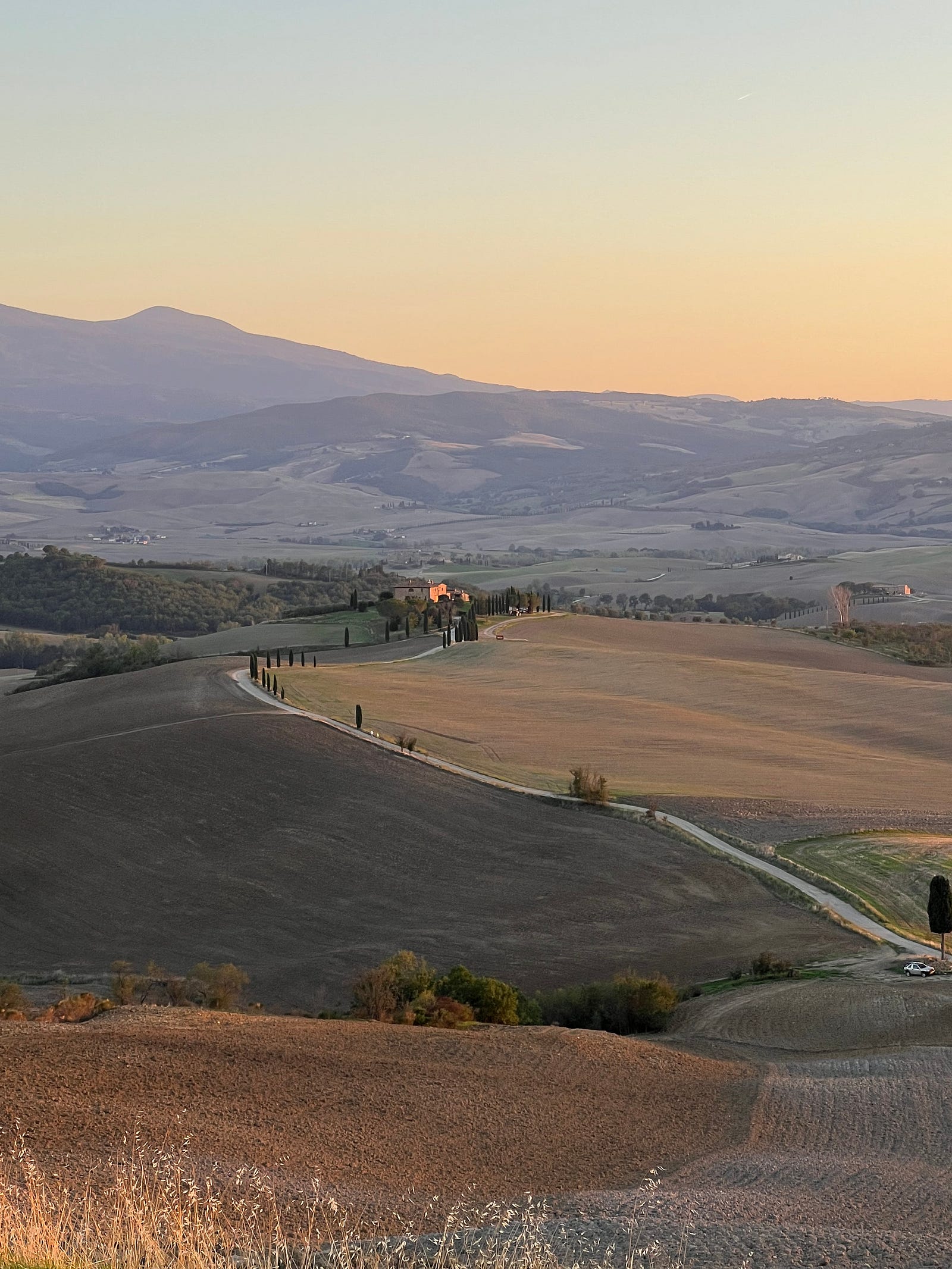 Photo of a Tuscan road running along a ridgeline among fields and hills during the 