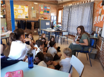 Una profesora le lee un libro a sus estudiantes en su clase.