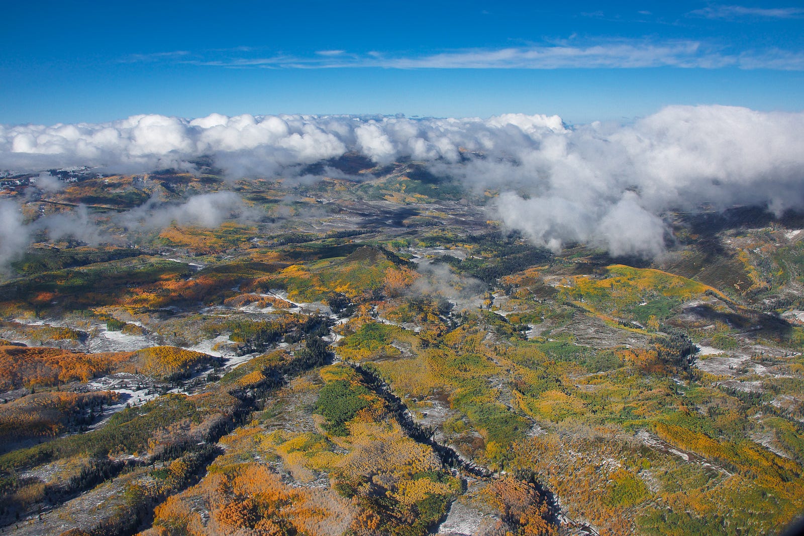 An aerial photo with colorful fall foliage, rivers, and partial cloud cover.