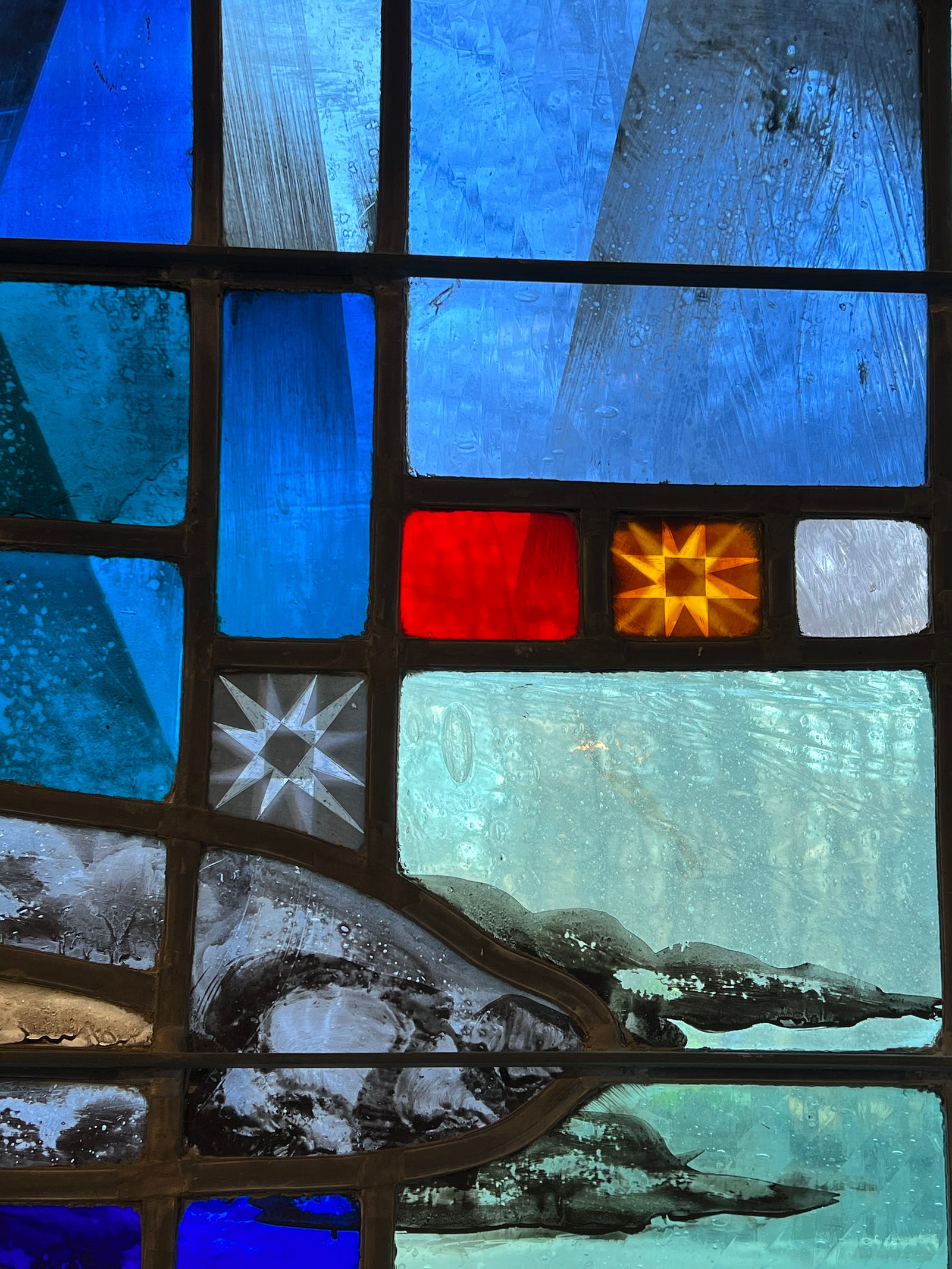 Photo of a piece of the Altar window at St Andrew’s Madison, CT showing, what seems to be, two bullet holes.