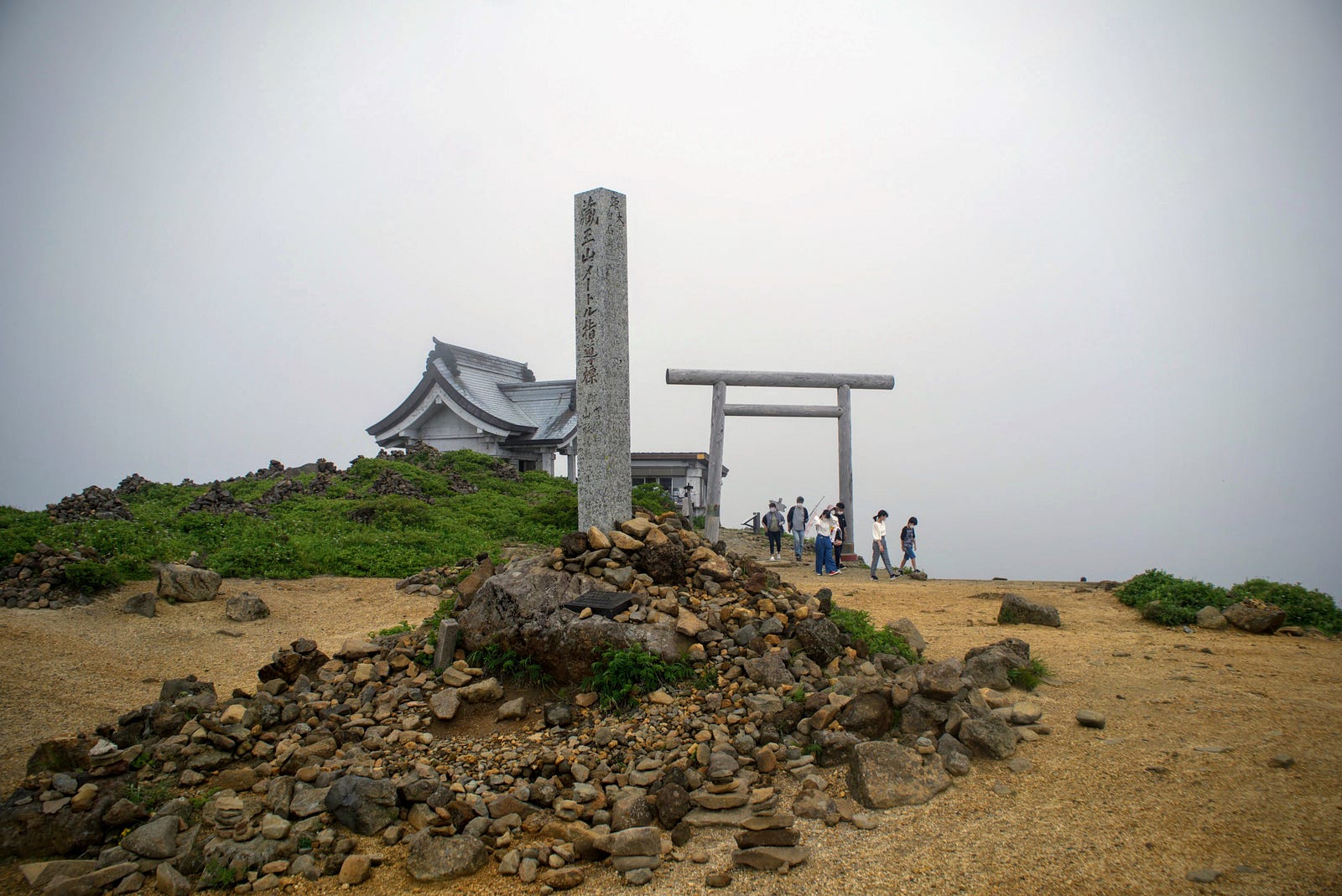 Katta-mine Jinja (shrine) on Katta-dake, Zao-san (Mt. Zao) with obelisk in the foreground, and building with torii gates in the background.