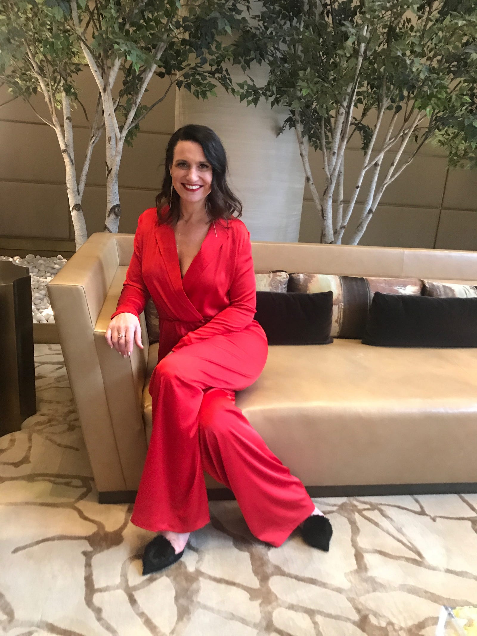 Tracy Matthews wearing the red silk jumpsuit by Bastet Noir