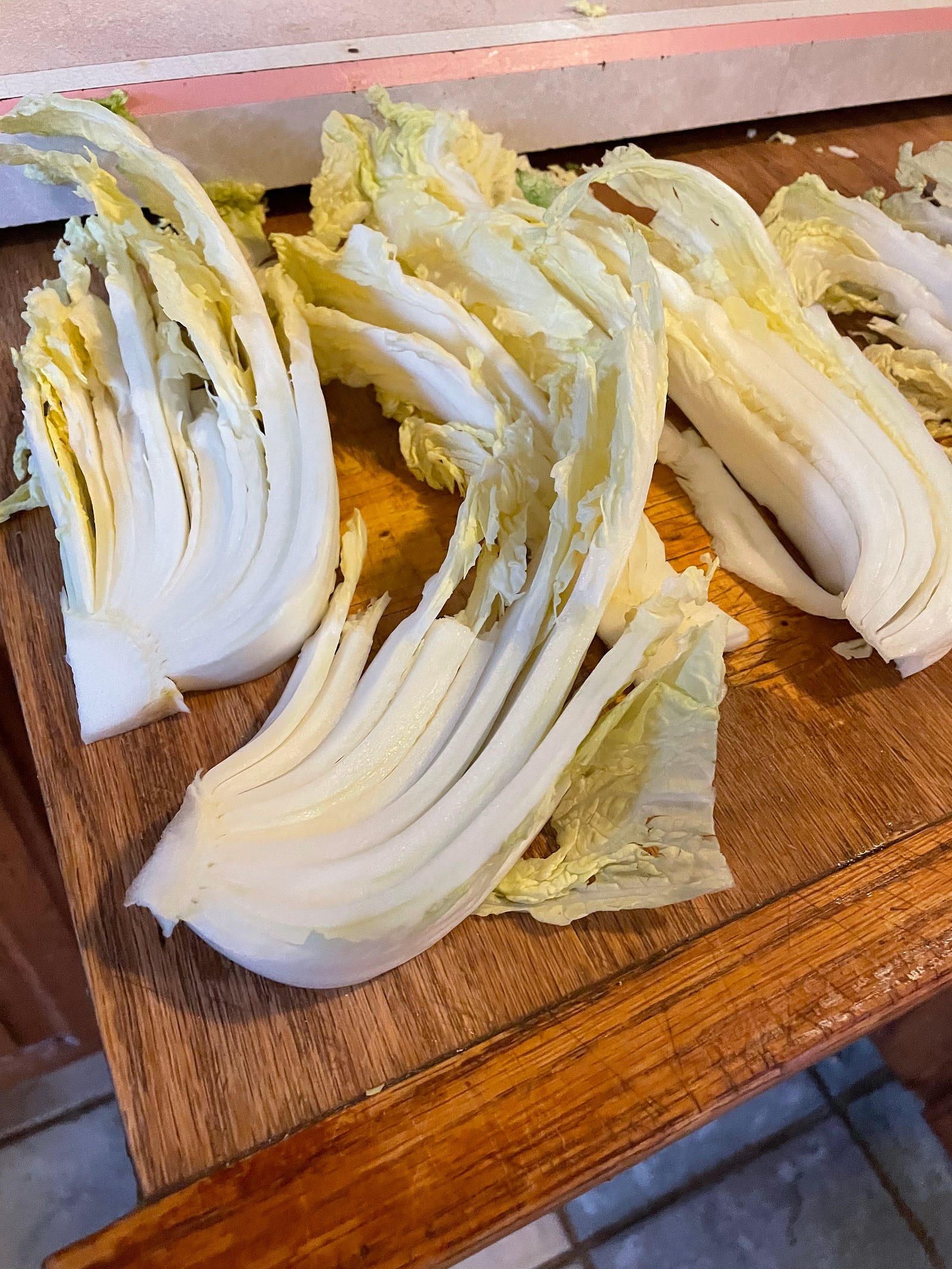 Four cabbage wedges thinly sliced on a cutting bord.