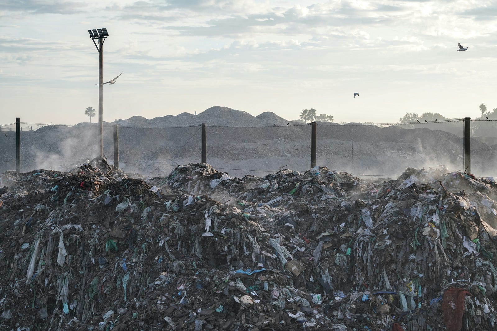 Mountains of waste in a landfill, highlighting the environmental impact of overproduction and consumption.