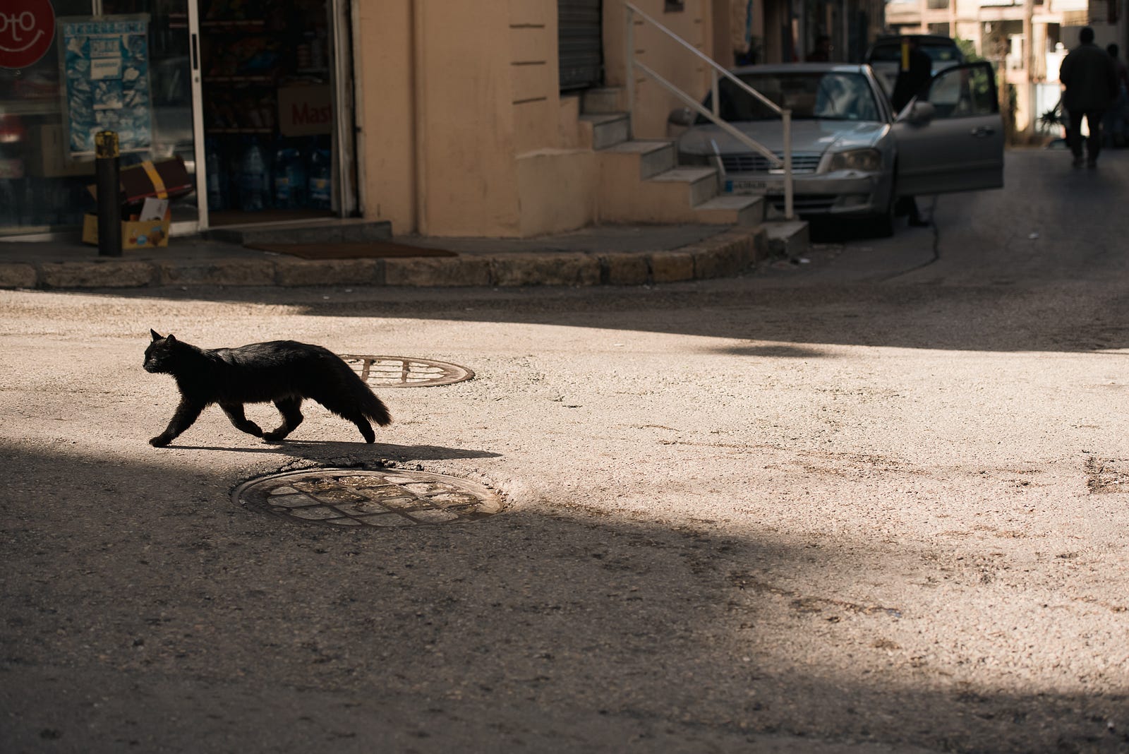 A black cat makes quick work of a street crossing.