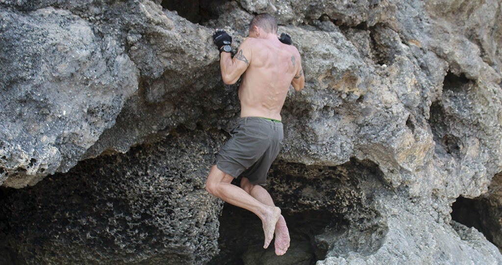 man doing pull-ups on a rock