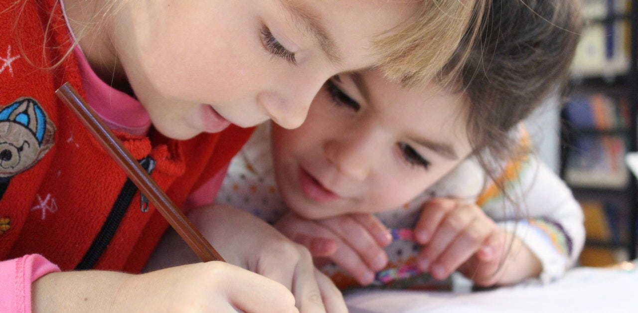 two young children coloring, writing, drawing, doing school work