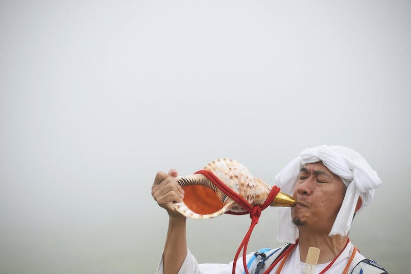 A master yamabushi mountain blows a conch shell on Mt. Gassan in Yamagata Prefecture