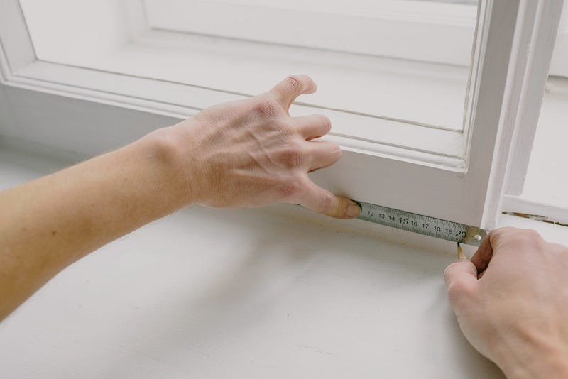 The math behind paper size: An aimage of a person measuring the dimensions of a window using a measuring tape.