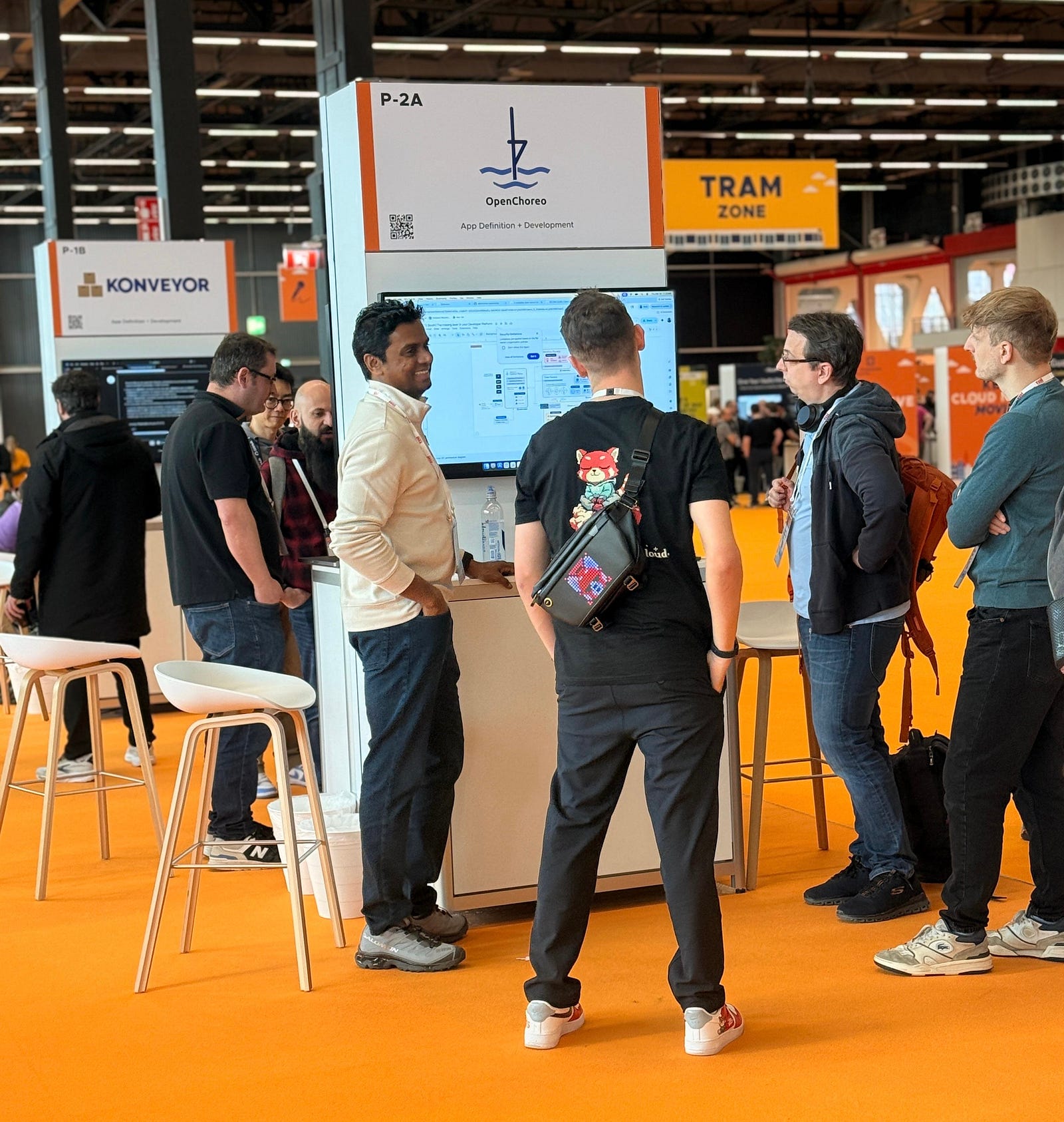 A group of people at a small kiosk at the CNCF Project Pavilion talking about new software project OpenChoreo.