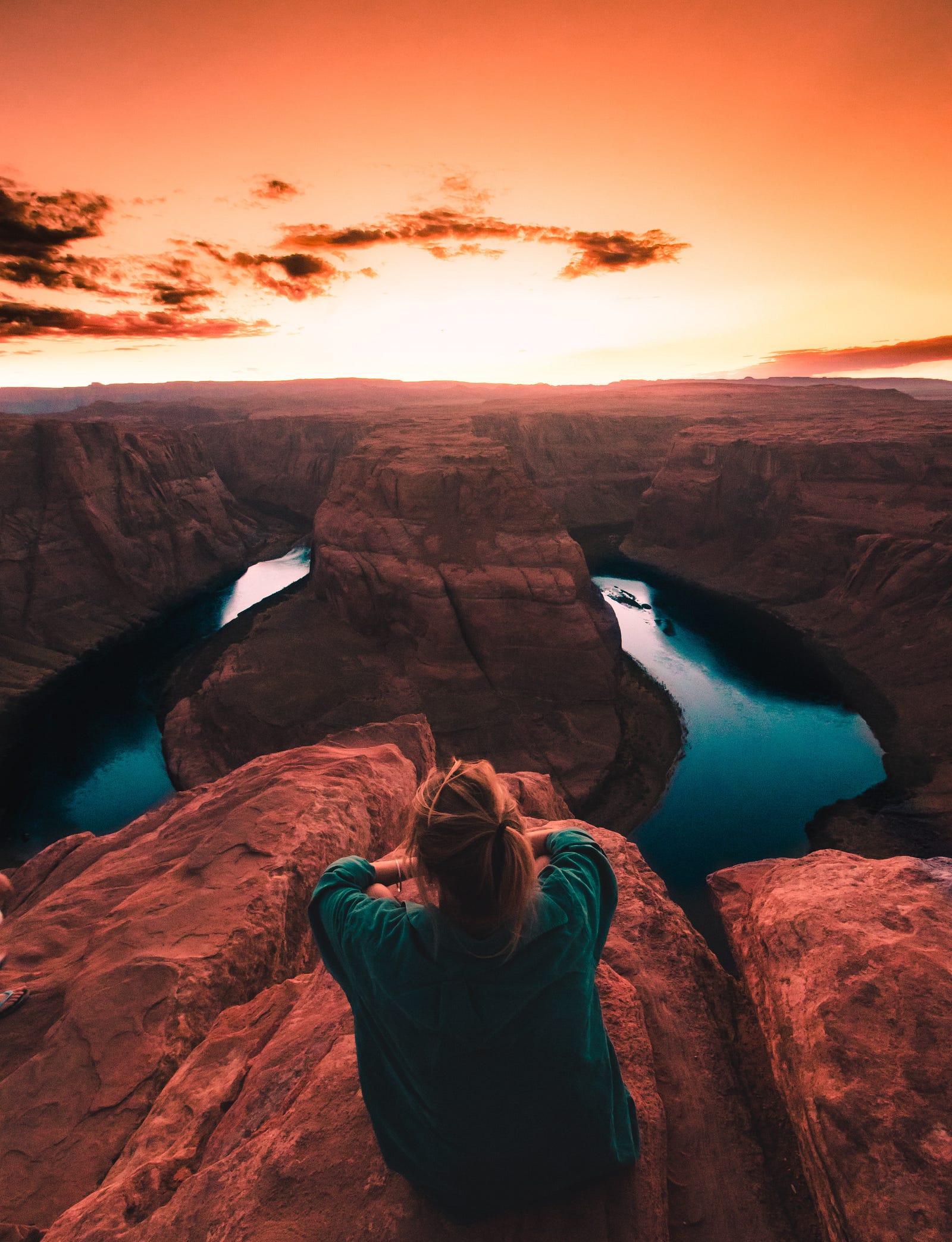 A woman laying on a roack over the grandcanyon at sunset