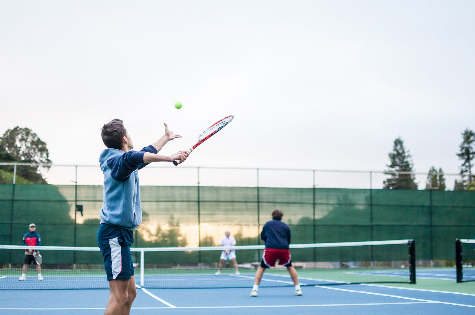 Four men playing doubles tennis