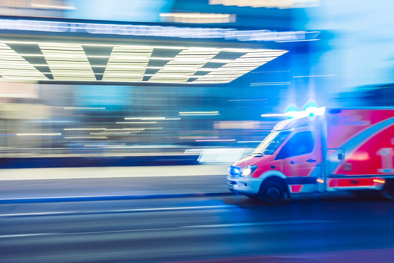 photo of a blurred red ambulance speeding across a street