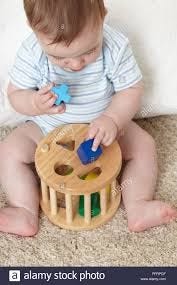 Child trying to fit blocks into appropriately shaped holes.