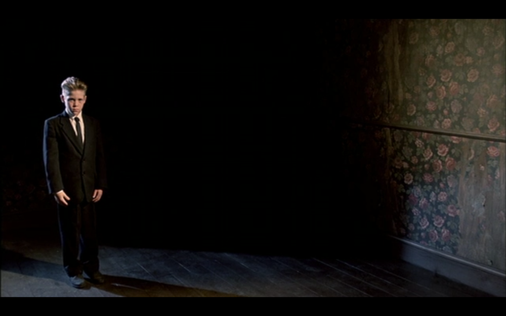 The Magician standing against darkness with the flowered wallpaper in Fire Walk With Me, 1992