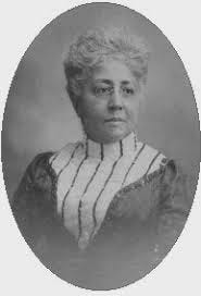 Black woman from the 19th century with round wire-frame glasses in a stripped and solid dress, poses for portrait.