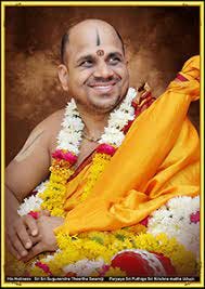Puttige swami smiling wearing saffron robes and a flower garland