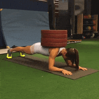 Woman doing a plank exercise with 4 25 kilogram plates on her back
