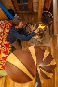 Zack Giffin making a fire in his tiny house under spiral stairs.